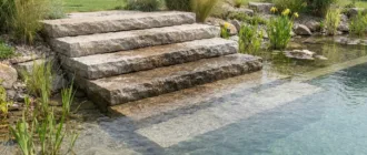 Teichtreppe aus Naturstein am Rand eines Schwimmteichs