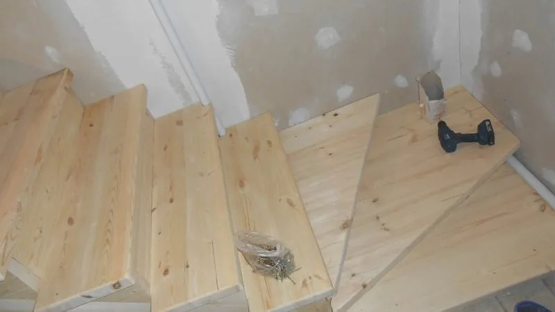 Handwerker montiert einen Geländerpfosten aus Holz an der Treppe