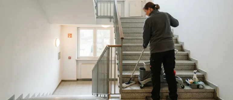 Professionelle Reinigungskraft wischt die Stufen in einem Treppenhaus